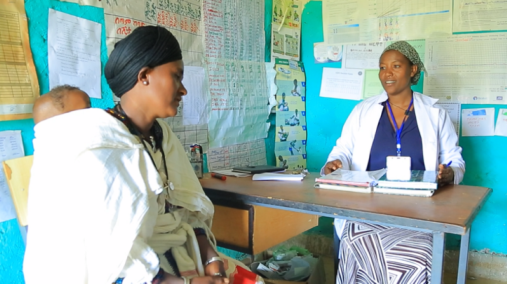 A health extension worker speaks with a mother at a health post