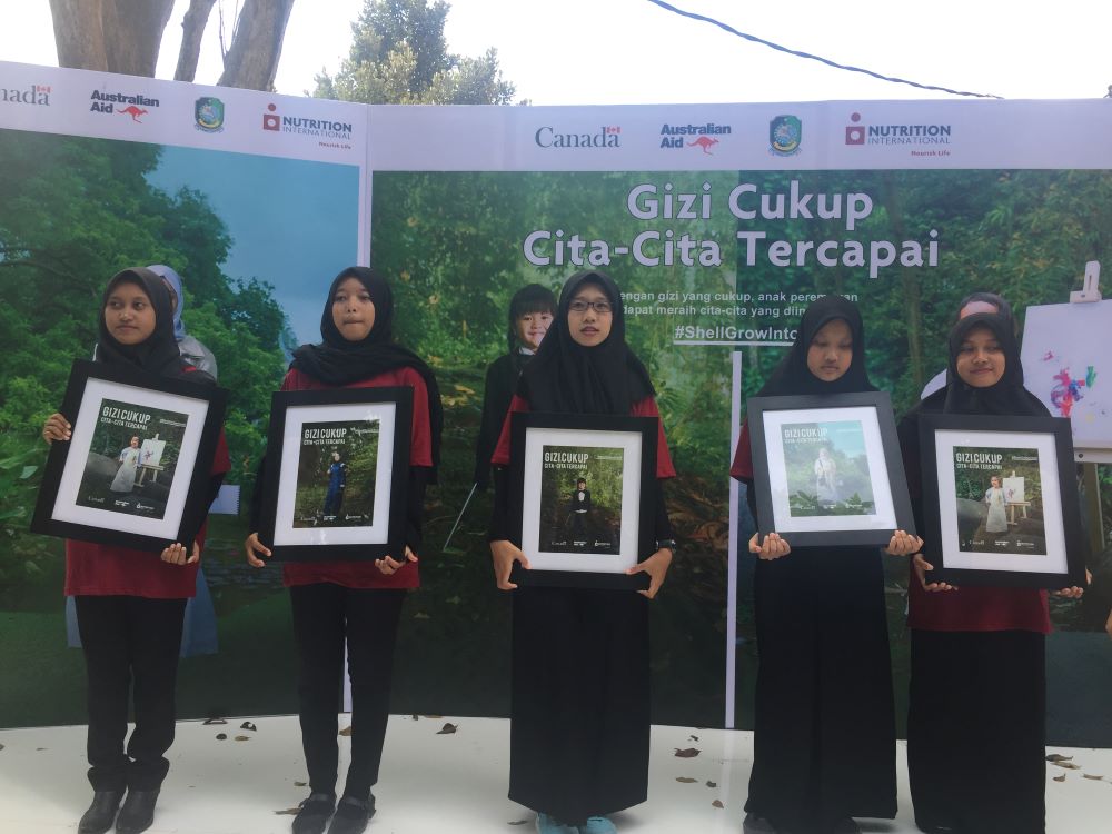 Girls at the SGII launch in Indonesia hold frames with campaign photos