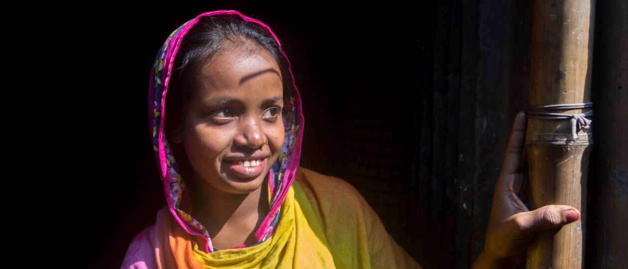smiling adolescent girl in doorway in Bangladesh