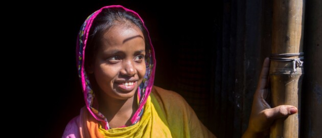 smiling adolescent girl in doorway in Bangladesh