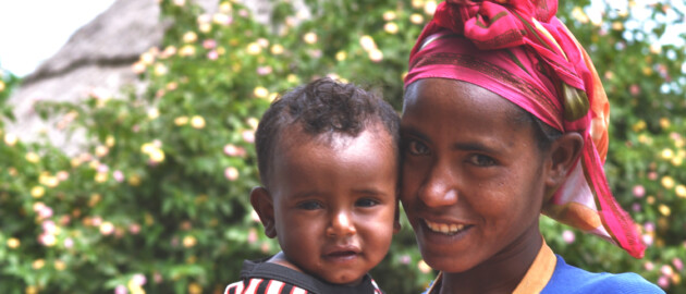Ethiopian mother wearing a red headscarf holding her baby.