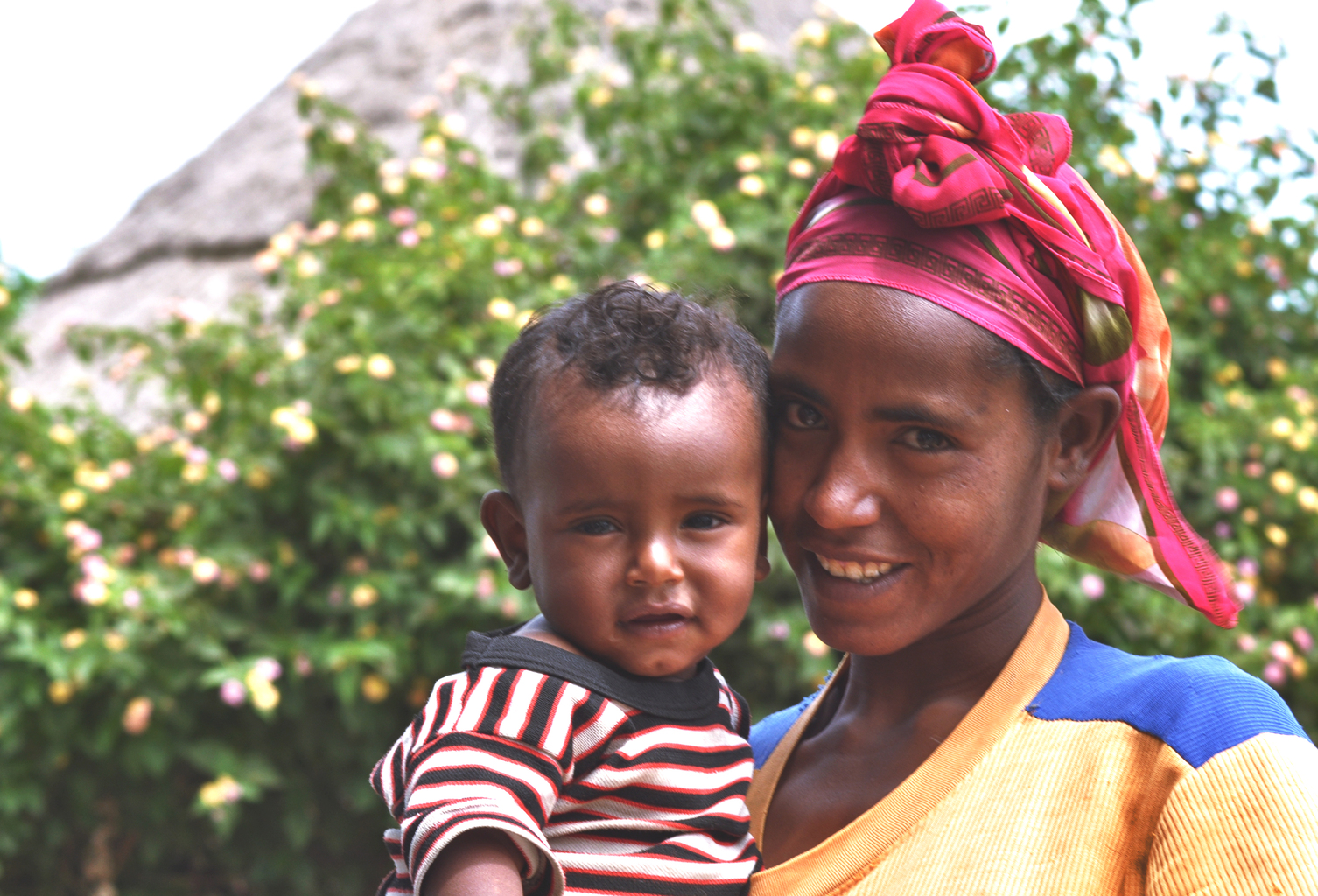 Ethiopian mother wearing a red headscarf holding her baby.