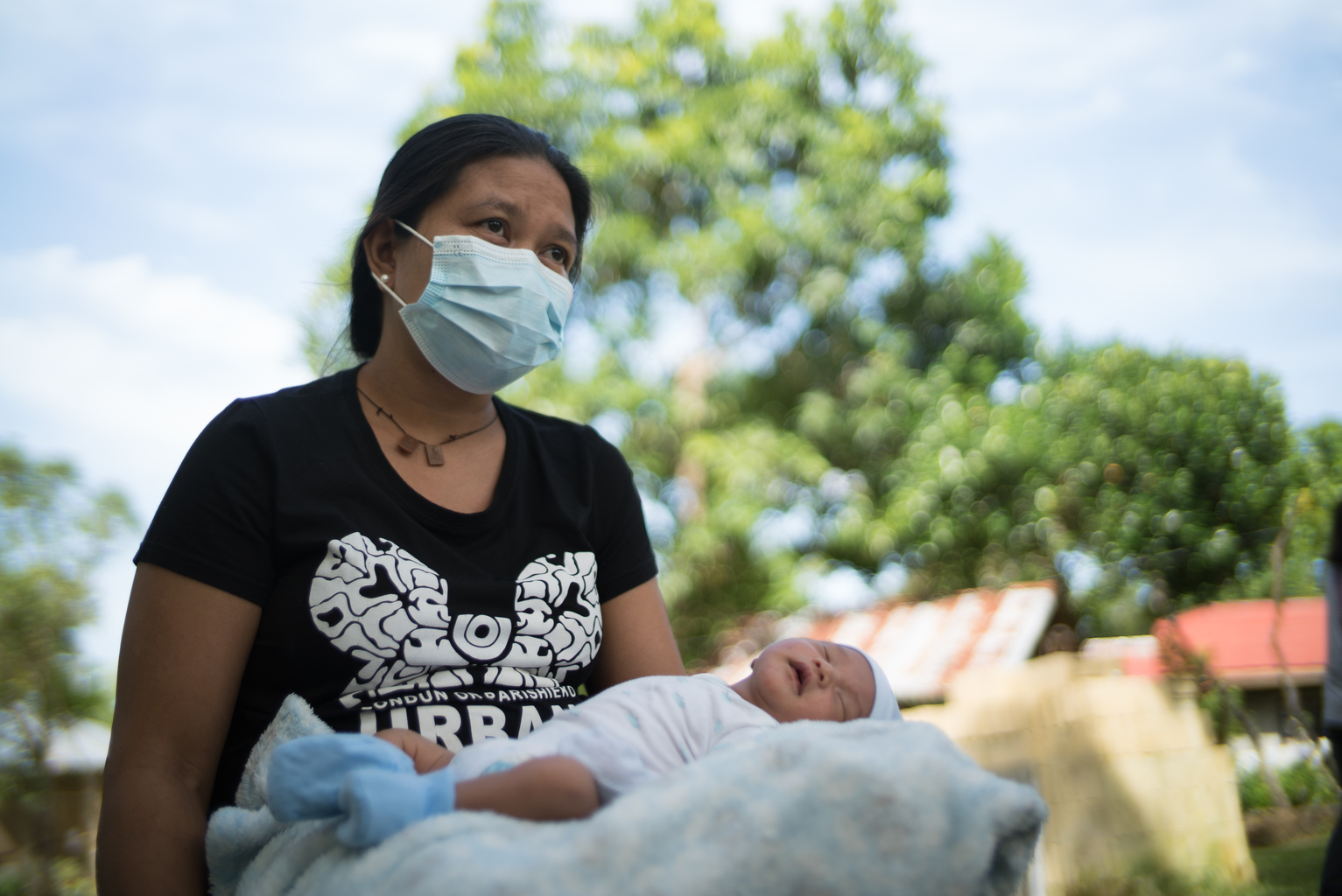 Mother wearing a mask holds her baby