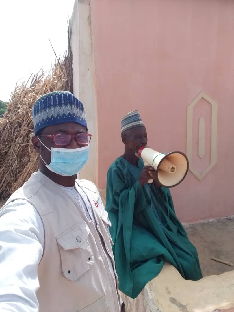 Nutrition International field staff with a town crier mobilizing for a vitamin A distribution in Nigeria