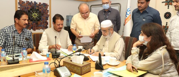 Pakistan man signing agreement surrounded by men and women