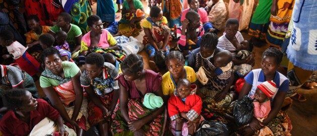 Women hold their children inside a clinic waiting to receive vitamin A supplementation in Malawi