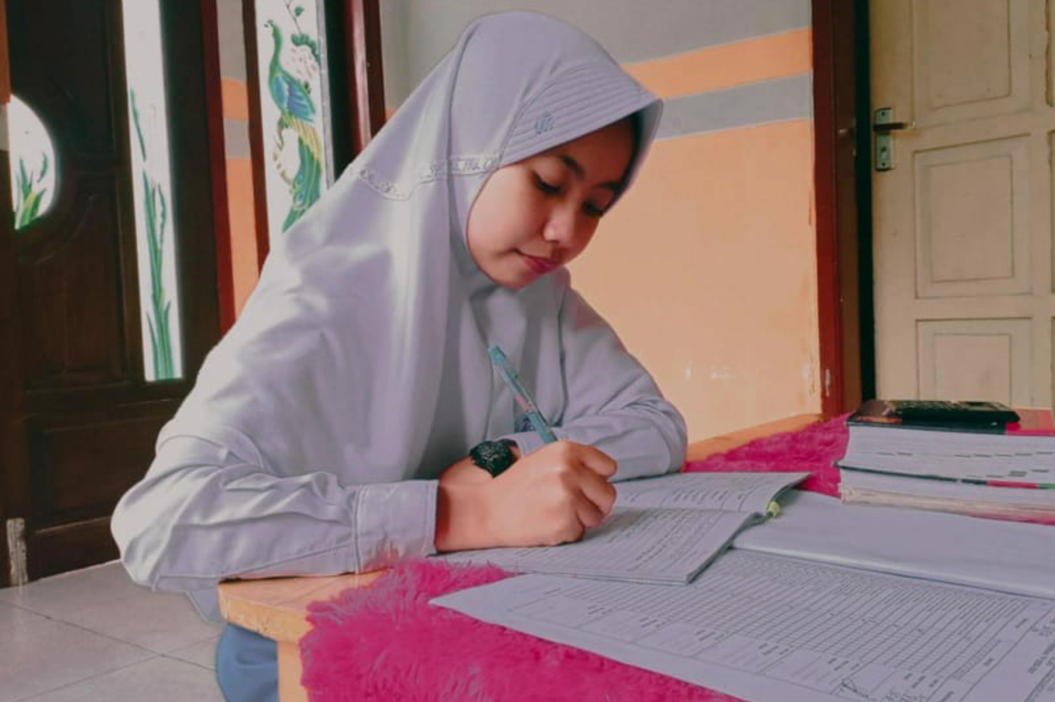 Student in Indonesia sits at a table and does her homework.