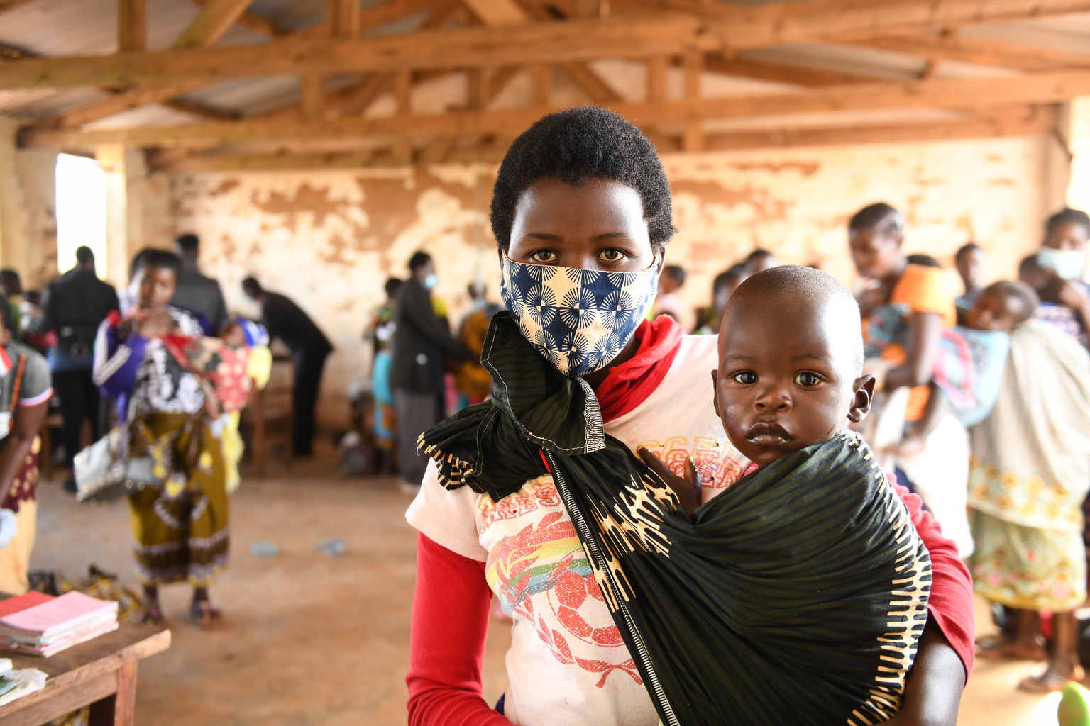 A mother wears a mask while taking her child to an under-5 health clinic in Malawi