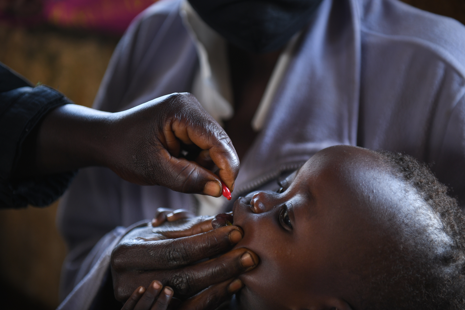 A child receives a vitamin A supplementation dose at a health clinic in Malawi