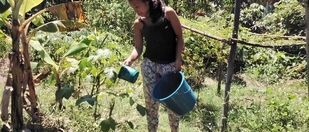 Woman standing outside watering her garden in the Philippines