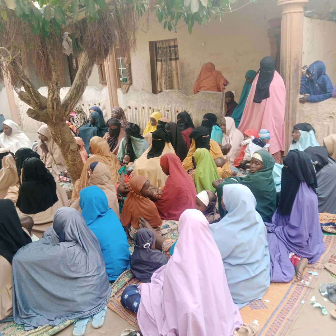 Women sit outside listening to a presentation