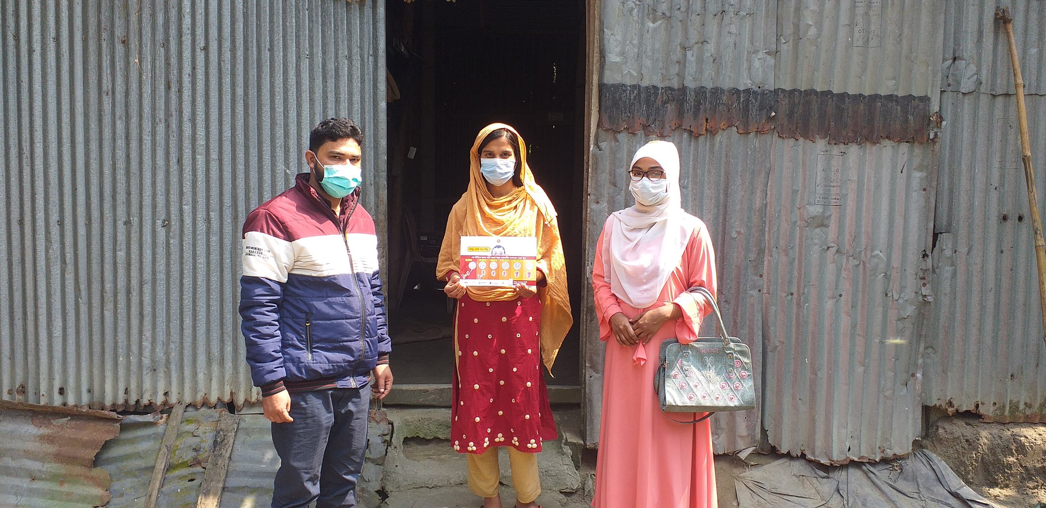 Three people stand outside in a row facing the camera