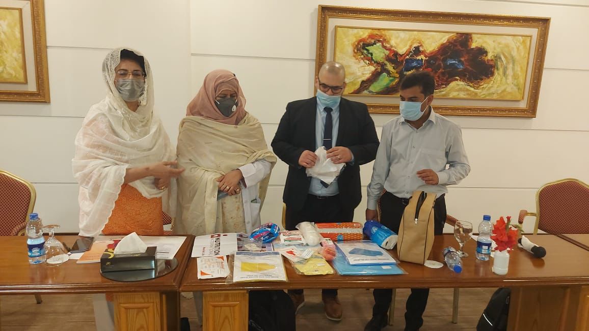 Quatre personnes se tiennent derrière une table et examinent les articles qui se trouvent dans les trousses accouchements des zones rurales du Pakistan.