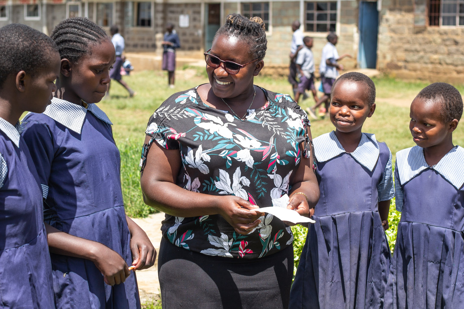 A woman speaks to students outside in the school yard.