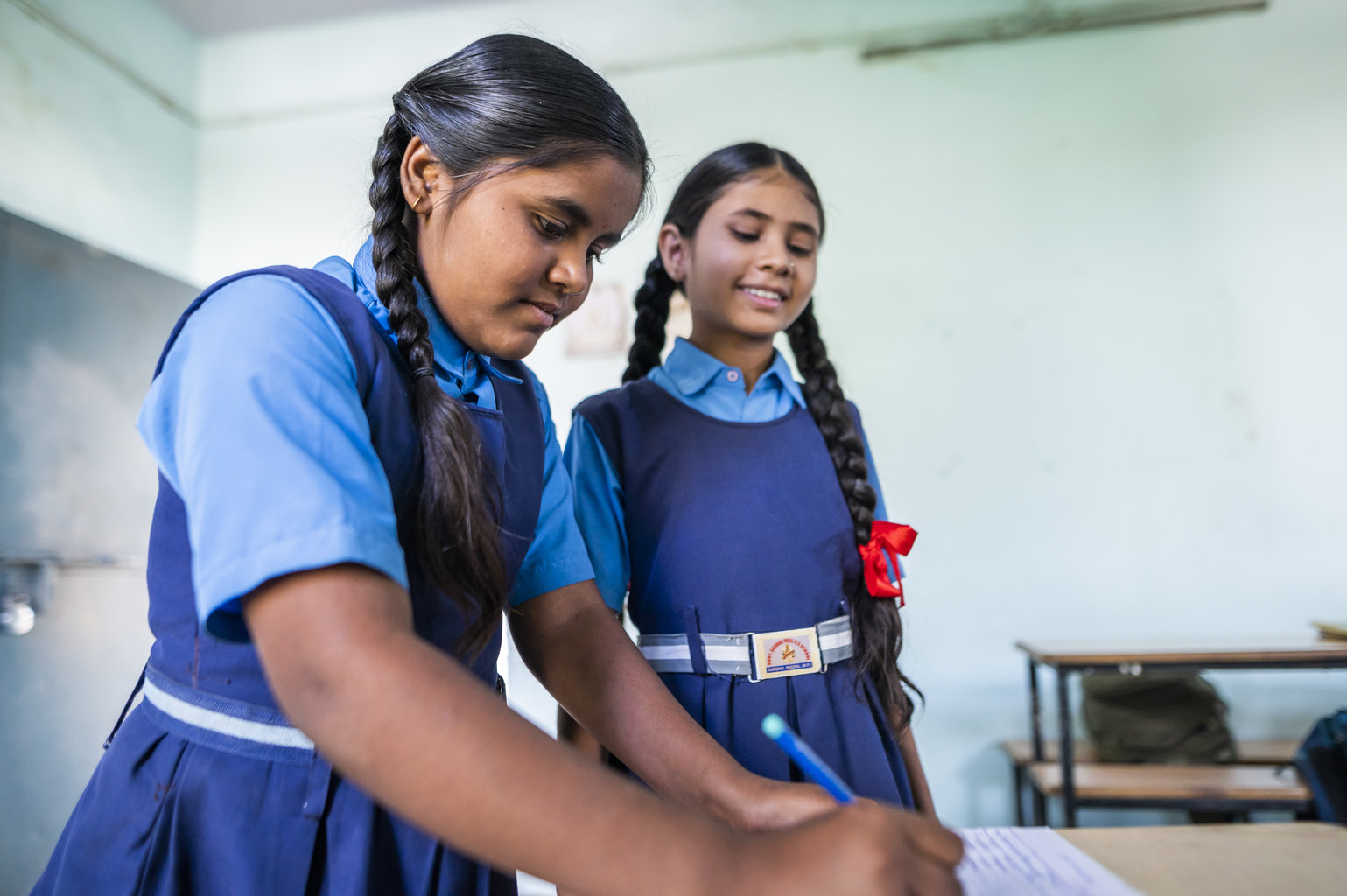 Two adolescent girls write in a notebook 