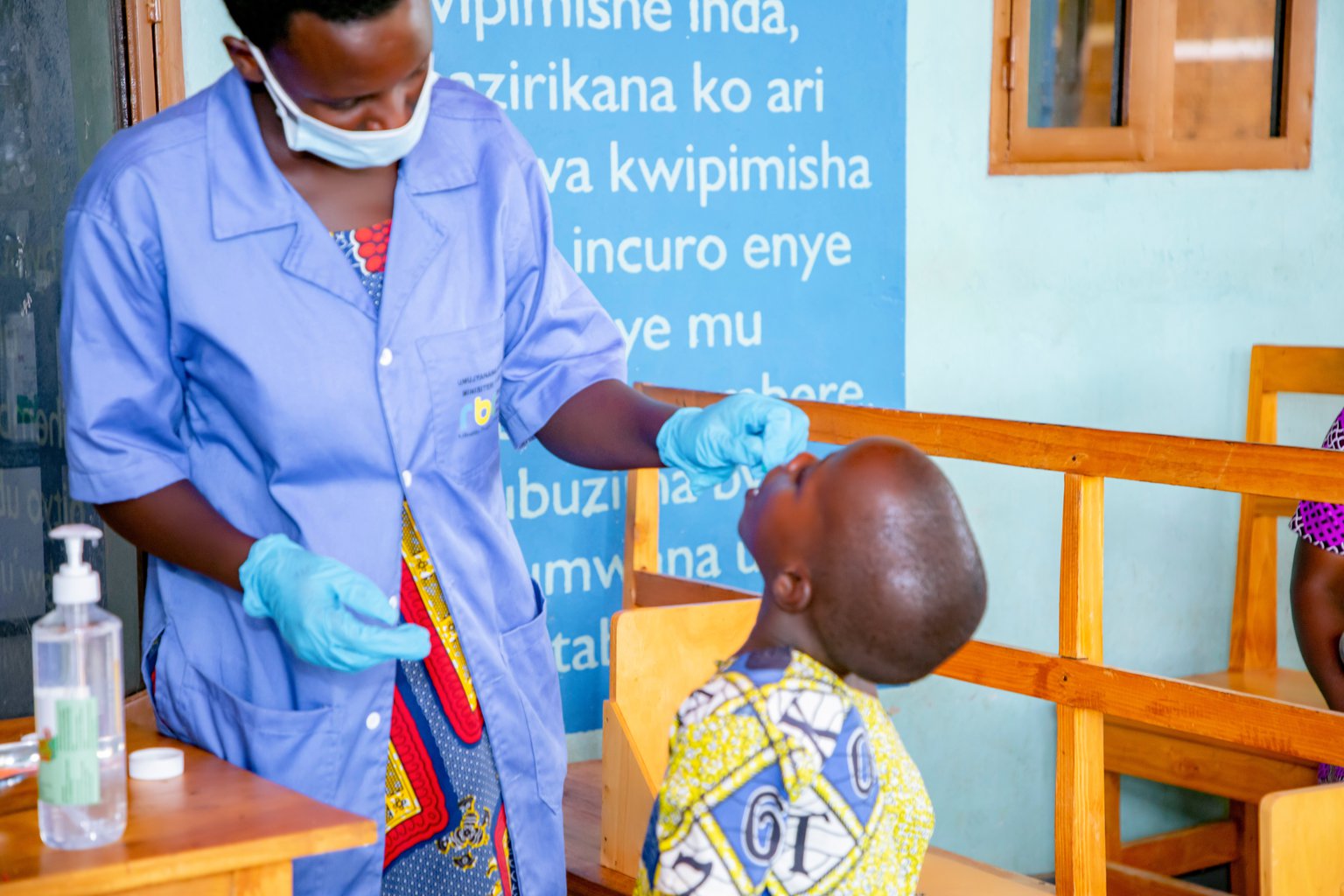 A woman administers a vitamin A supplement to a child.