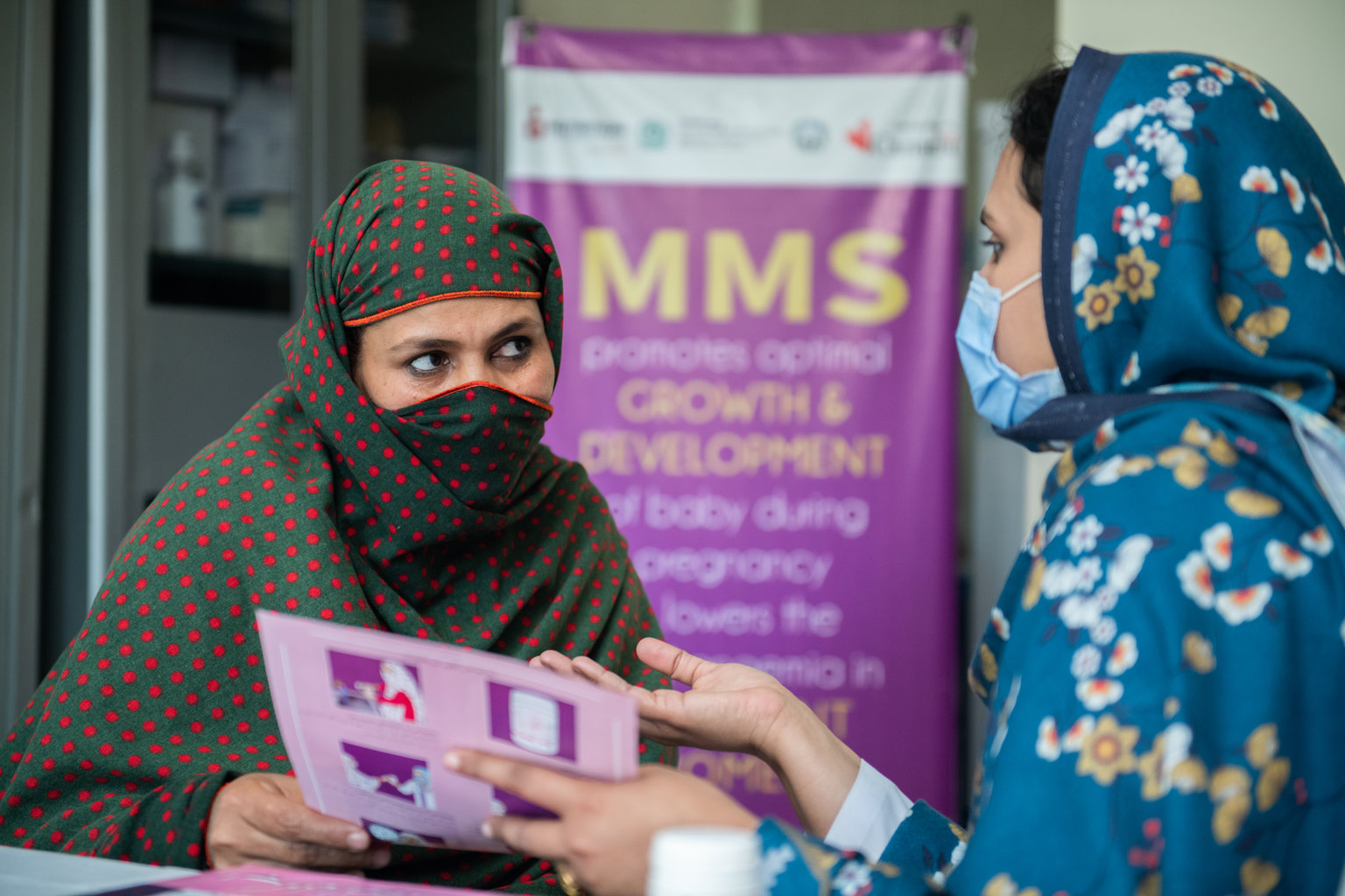 A woman showing a pamphlet to another woman