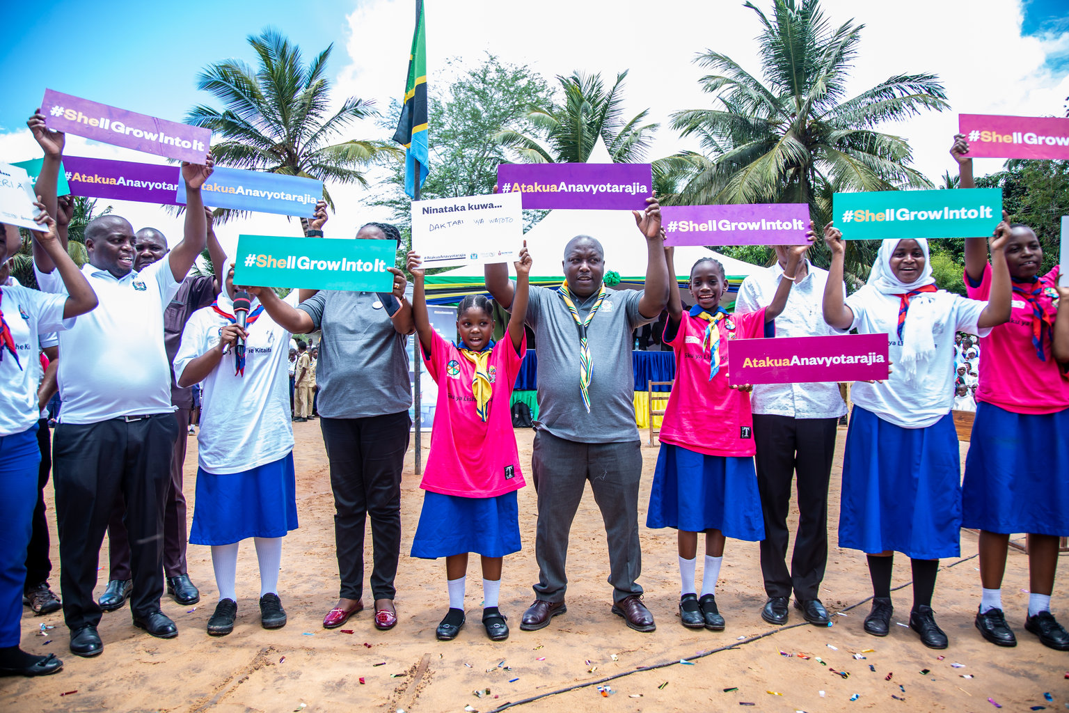 A group of people facing the camera holding coloured signs over their heads