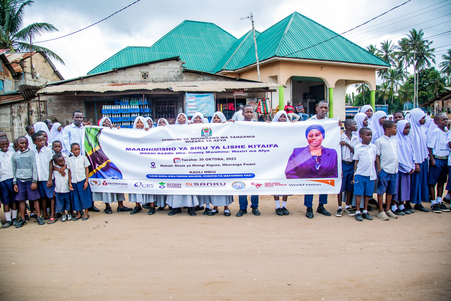 A group of adolescents face the camera holding a banner