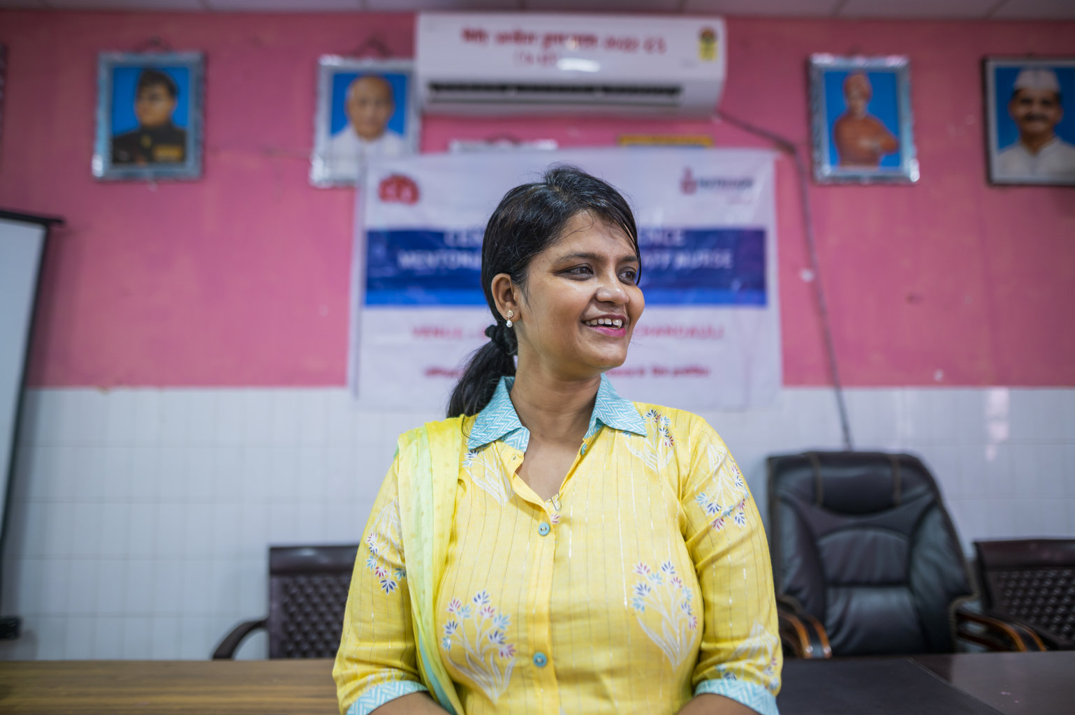 A woman smiles presenting at the front of a room