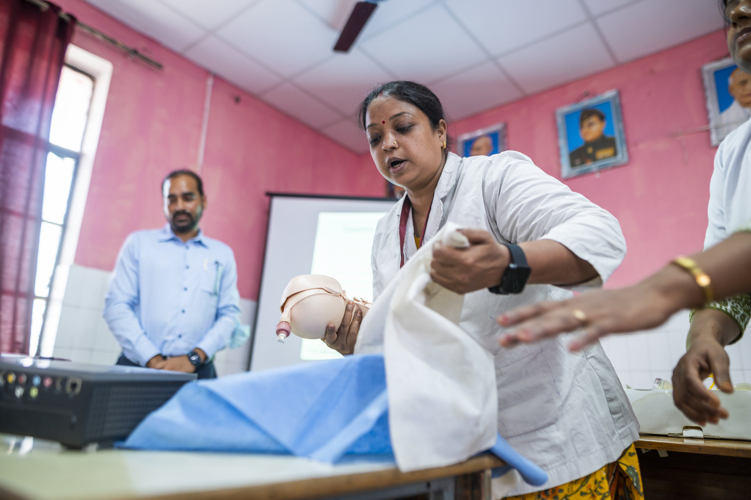 A healthcare worker demonstrates newborn care at a training session in a hospital.