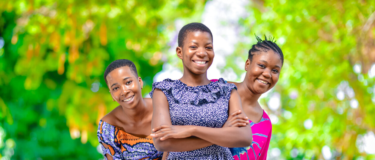 Three women standing in a line, smiling.