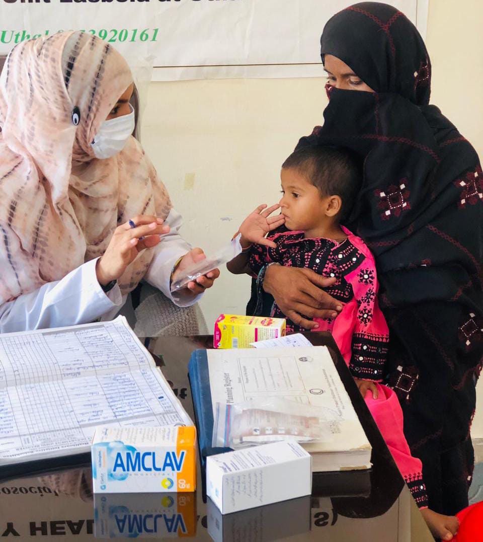 A health care worker provides counselling and treatment of a co-package of zinc and LO-ORS to a mom holding a three-year-old for diarrhoea.