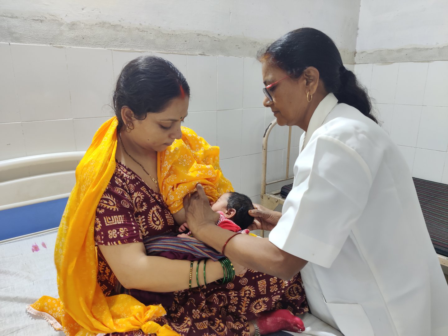 A nurse supports a mother to breastfed her newborn.