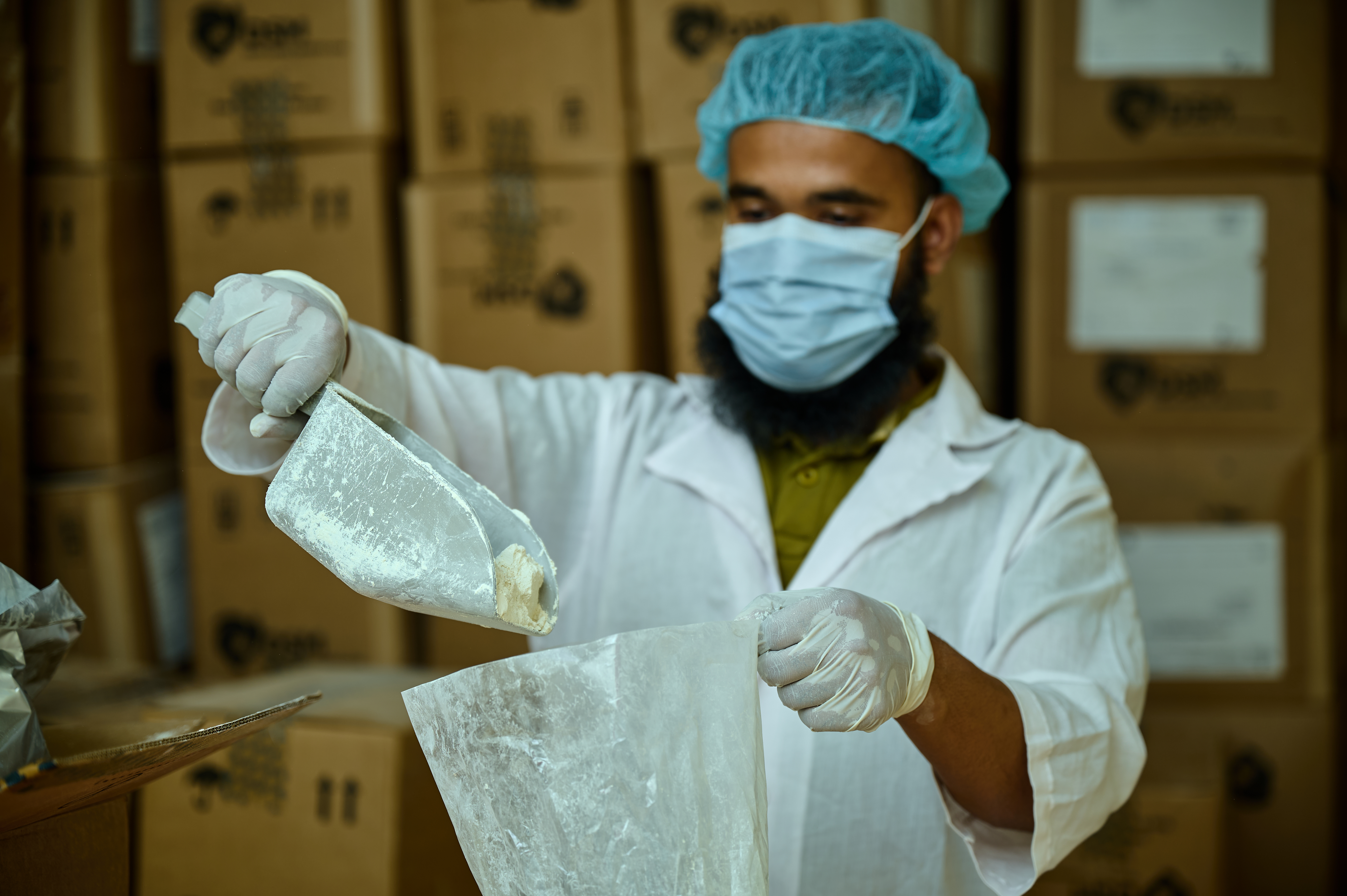 A worker measures a micronutrient premix in a factory in Bangaldesh that will be used to fortify rice.