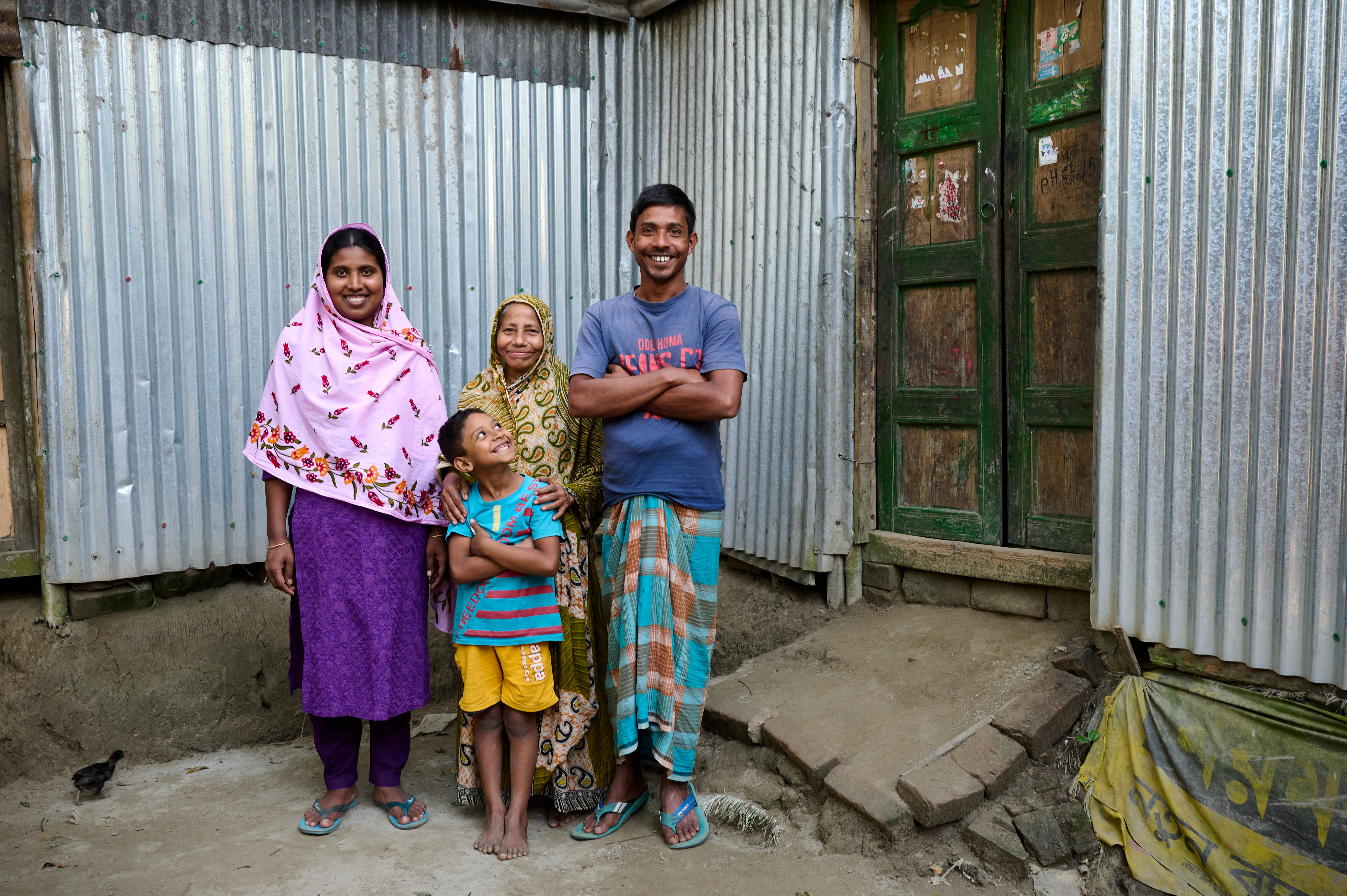A woman stands with her mother-in-law, husband and child. All four are smiling and posing for the camera.