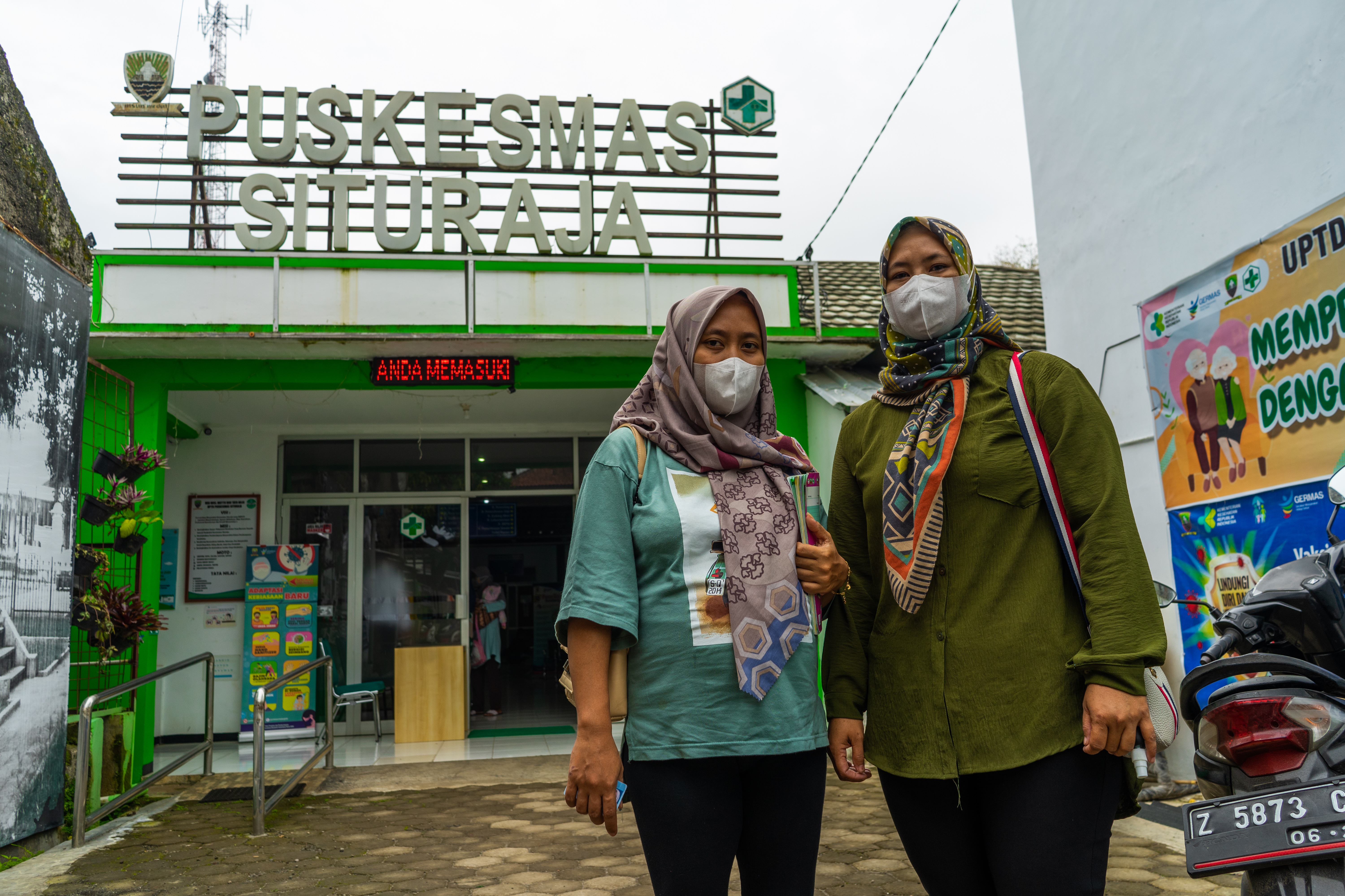 Two women stand facing the camera in front of a health center