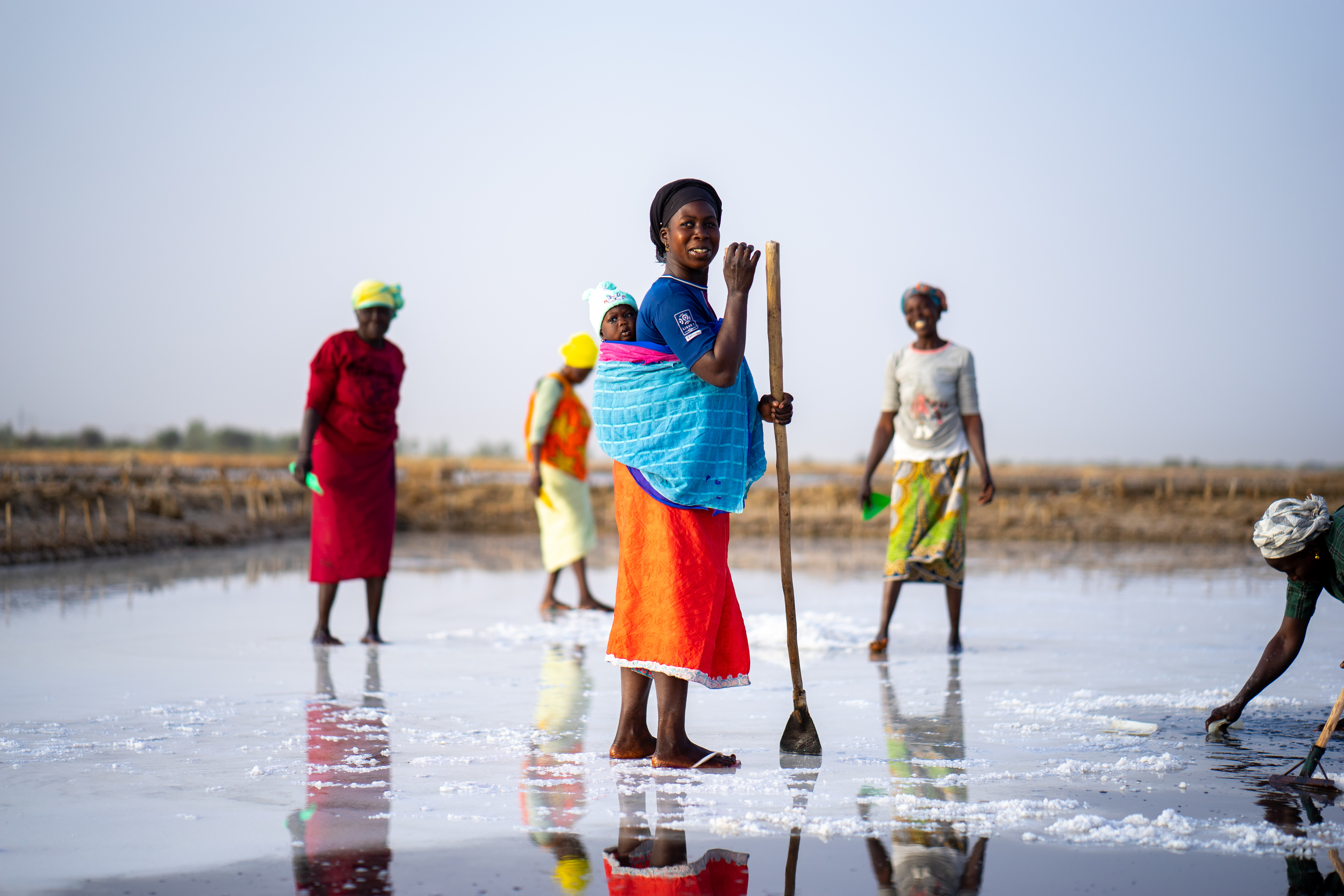 A woman stands in the middle of a salt field in Senegal.