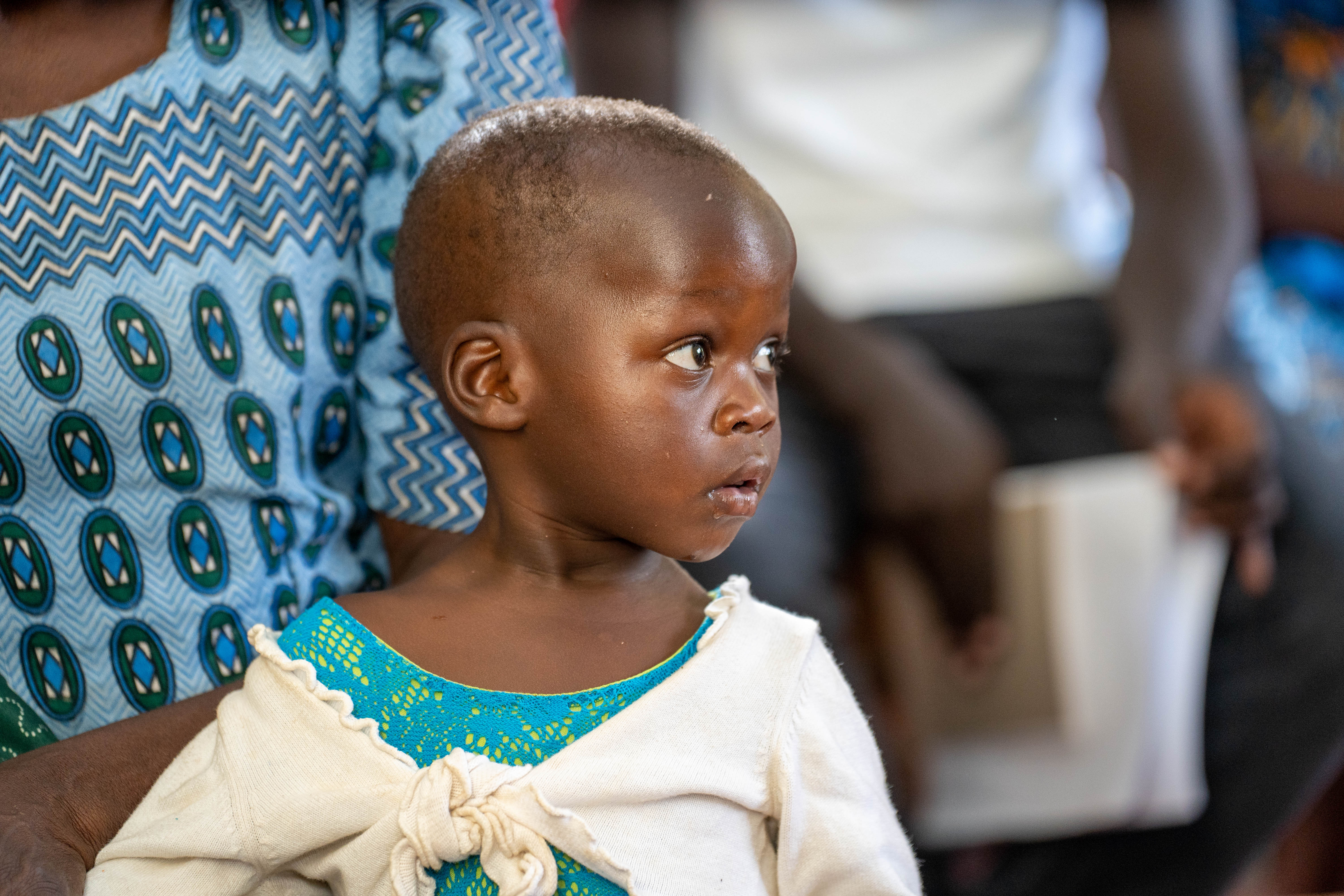 A young child sitting on their mother's lap.