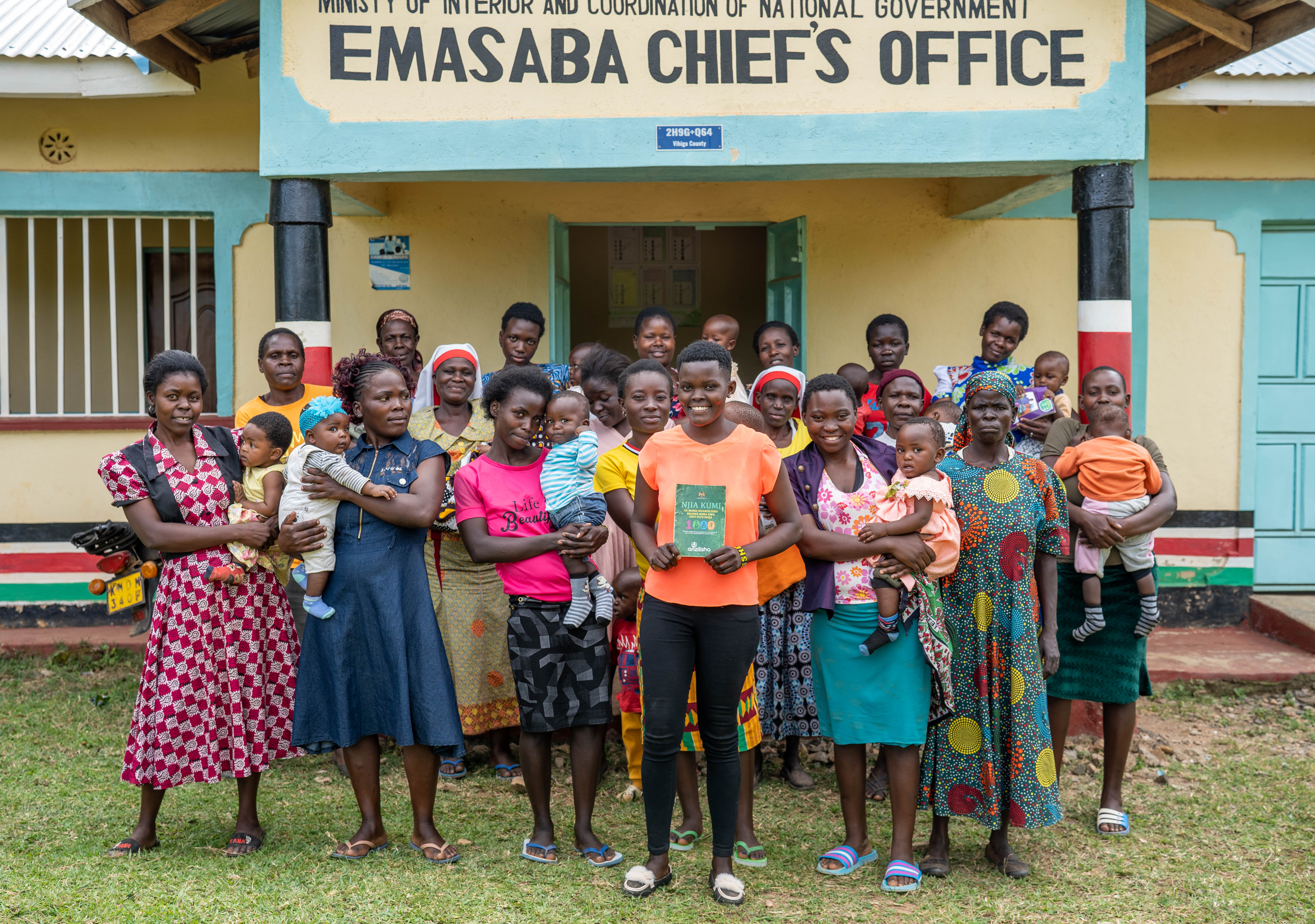 Member's of the mother-to-mother support group stand in front of the Embasaba Chief's Office
