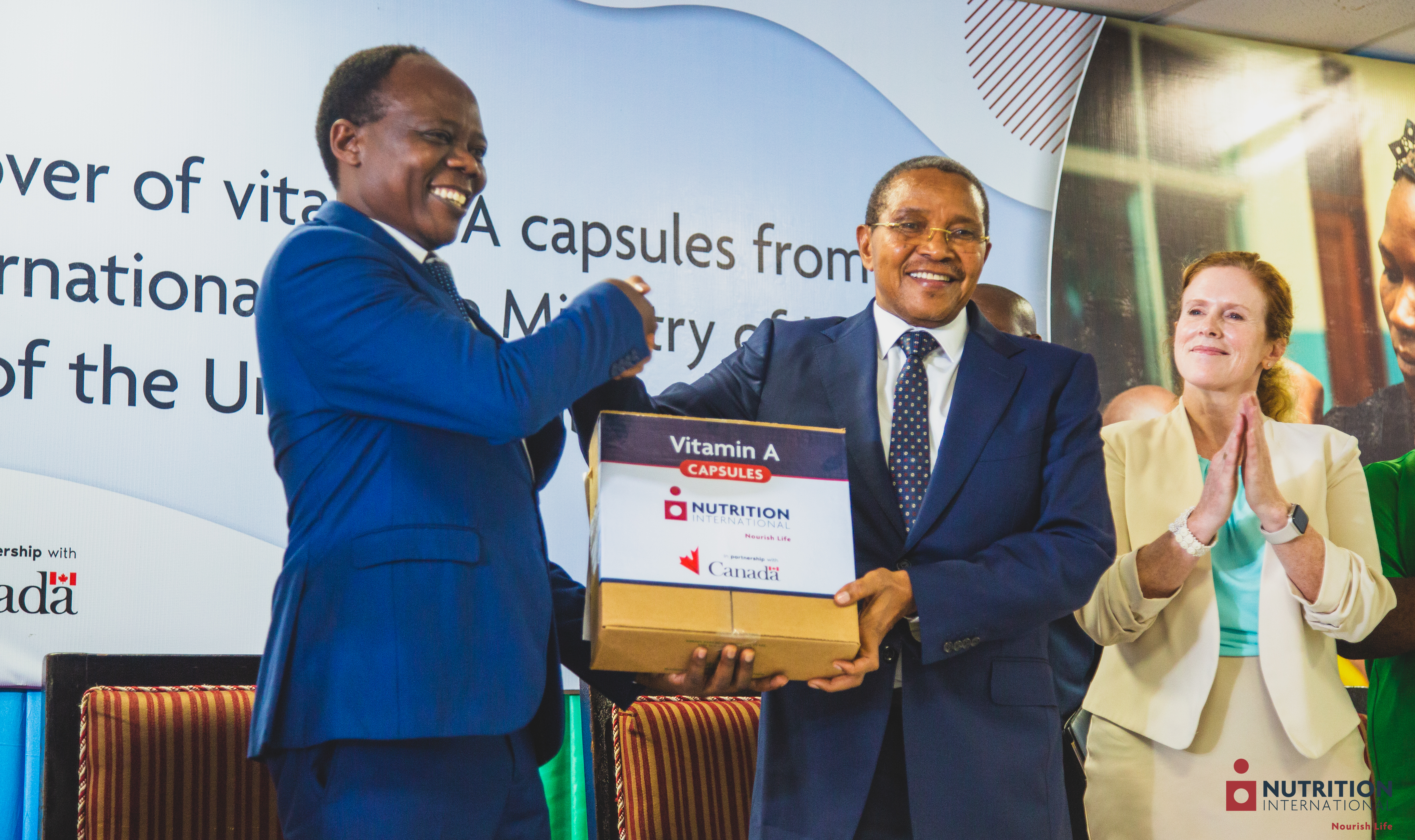 A man shakes another man's hand while holding a box.