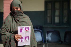 Sonia Hamid standing in front of camera holding up MMS brochure. 