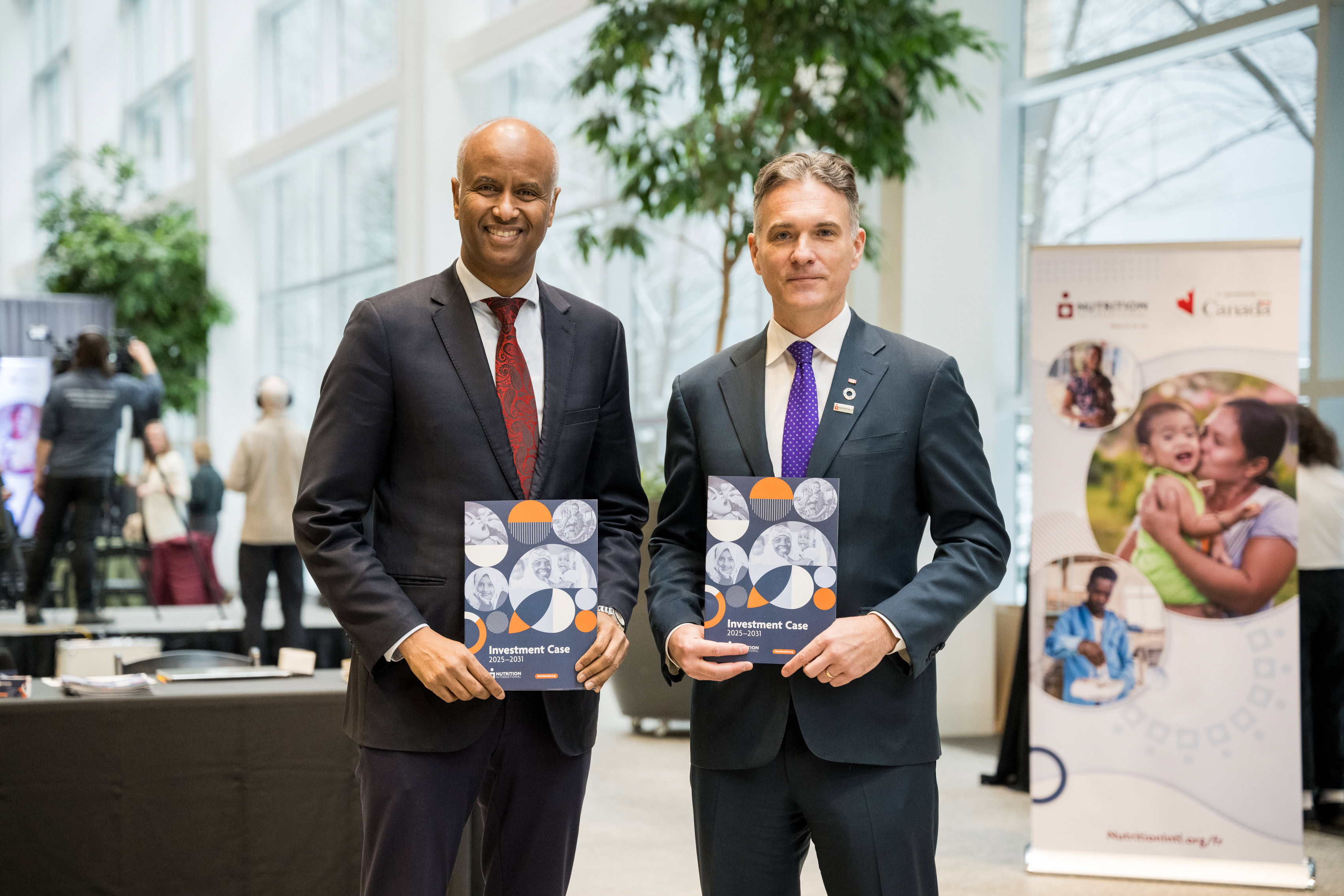 Deux hommes tenant des brochures face à la caméra