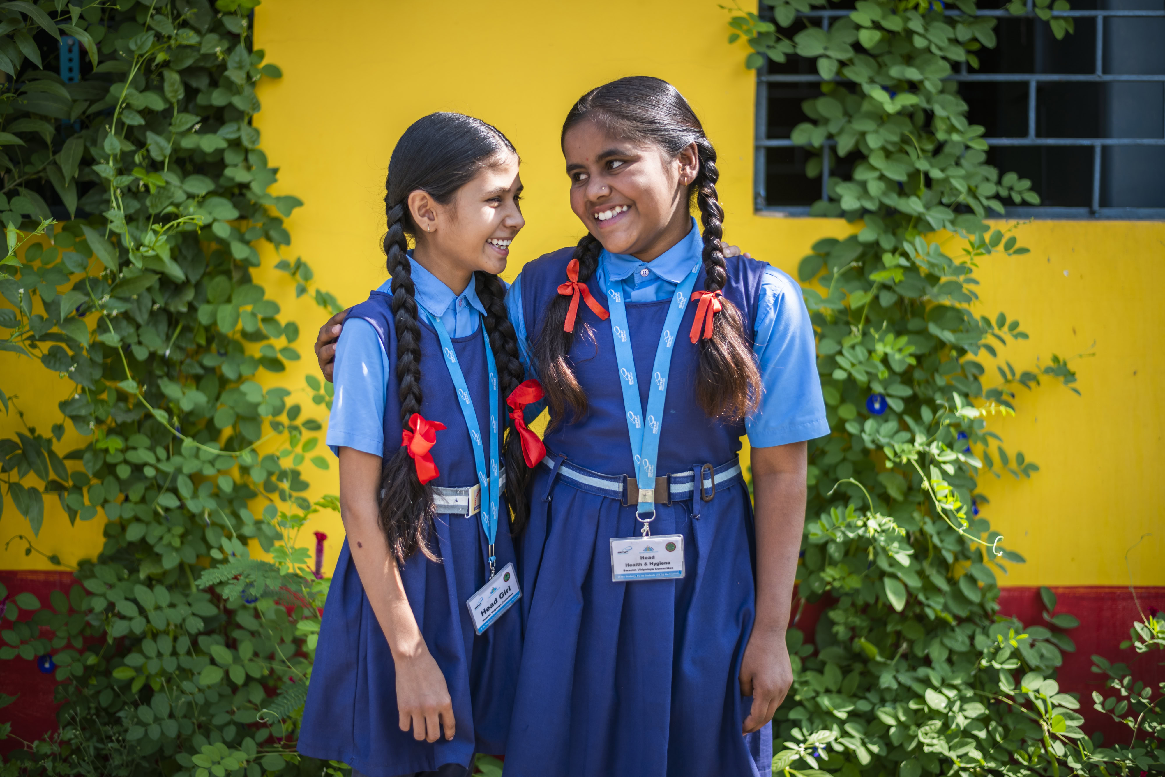 Two adolescents embrace, smiling side by side.