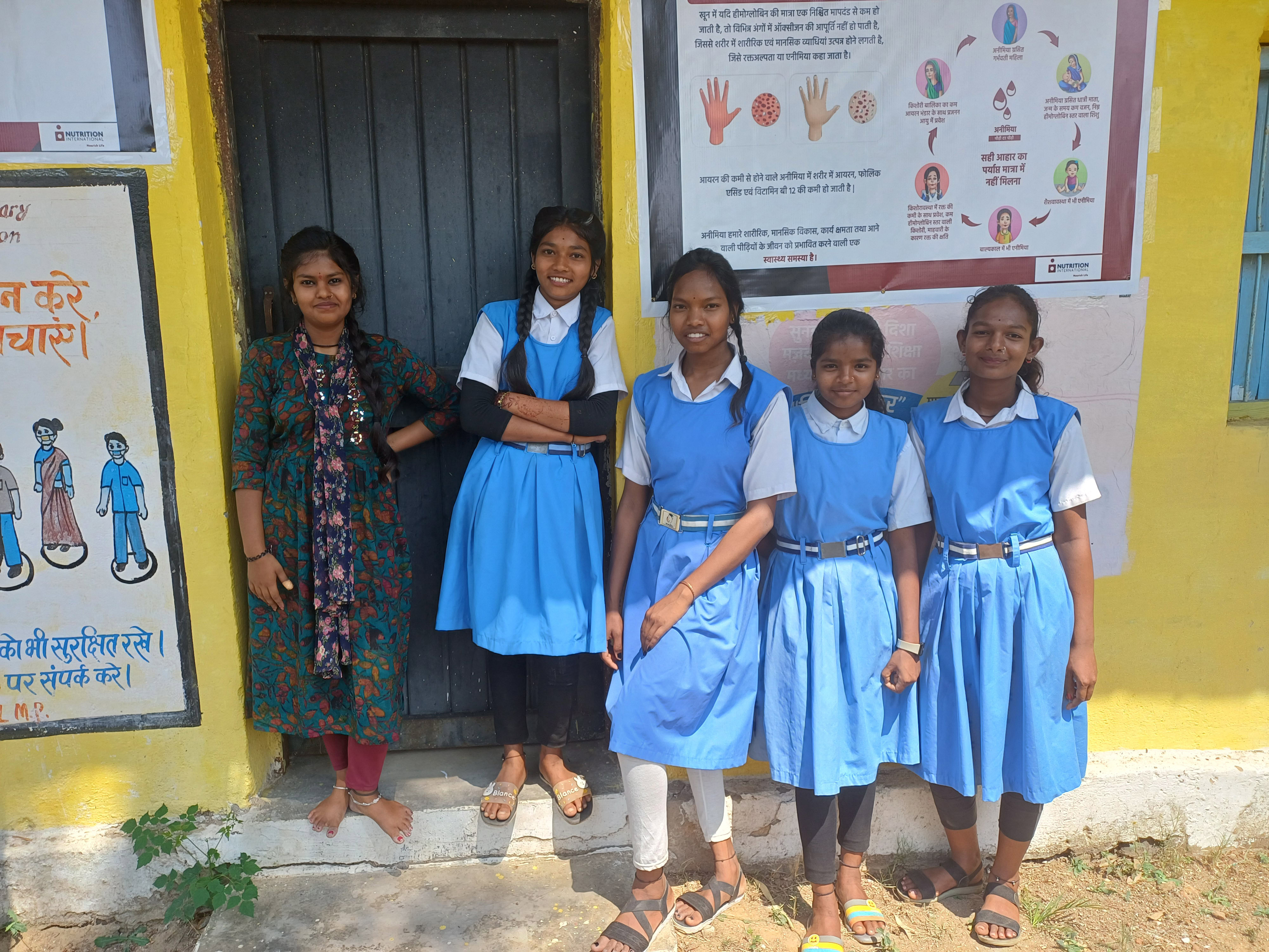 A group of students in their school uniforms stand outside smiling to the camera