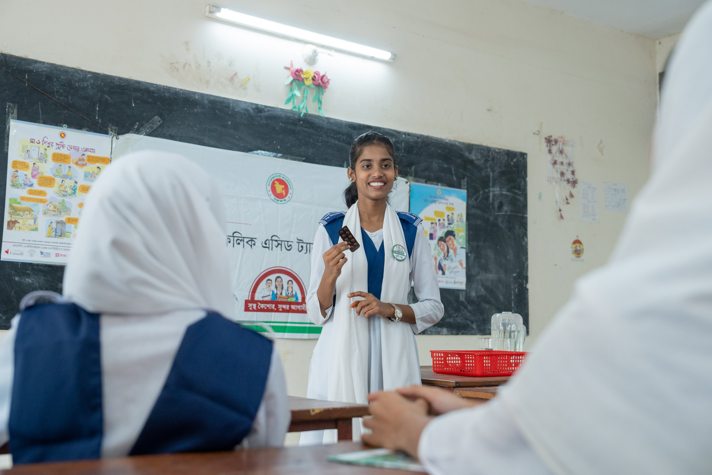 A female student stands in front of her classmates and speaks with confidence.